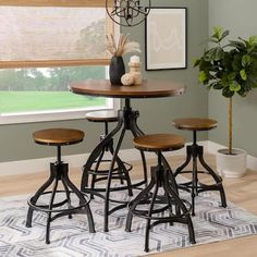 a dining room table with four stools and a potted plant in the corner