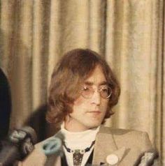 a man in a suit and tie standing next to a curtain with his hands up