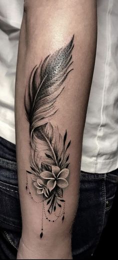 a black and white tattoo with a feather on the arm, which has a flower in it