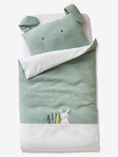 a green and white bedding set with a bunny in the pocket on it's side