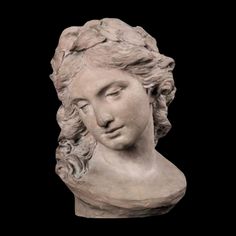 a white marble bust of a woman with curly hair and eyes closed on a black background