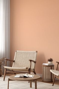 a living room with two chairs and a table in front of a pink painted wall