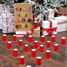 a bunch of red cups sitting on top of a wooden floor next to a christmas tree