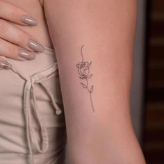 a woman's arm with a small rose tattoo on the left side of her arm