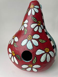 a red vase with white and yellow flowers painted on it