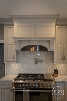 a stove top oven sitting inside of a kitchen next to white cabinets and counter tops