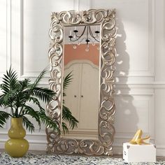 a mirror sitting on top of a table next to a vase and potted plant