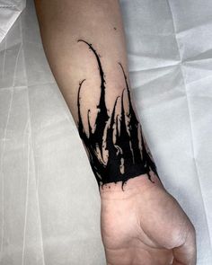 a black and white tattoo on the arm of a person's left hand, with plants growing out of it