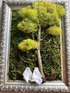 a small tree in a silver frame with moss