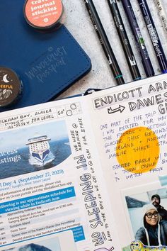 bobo design studio's wanderlust passport travel journal opened up to showcase its journal spread featuring hand lettering, doodles, and travel pamphlets. the journal is surrounded by another journal, washi tape featured in the wanderlust passport starter kit, and tombow pens