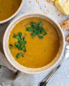 two bowls filled with soup and garnished with parsley next to some bread