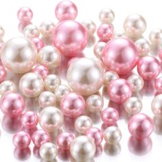 pink and white pearls are scattered on a white surface