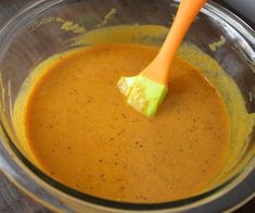 a wooden spoon in a glass bowl filled with sauce