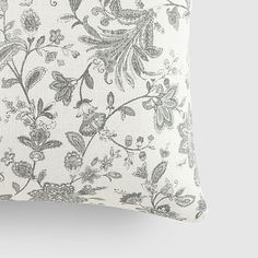 a white and blue floral pillow on a gray background