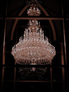 a large chandelier hanging from the ceiling in a dark room with arched doorways