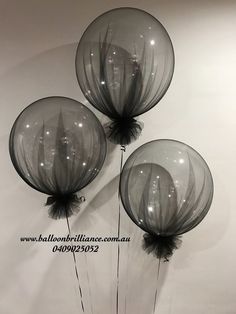 three clear balloons with black feathers on them