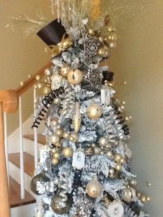 a white christmas tree with gold and silver ornaments