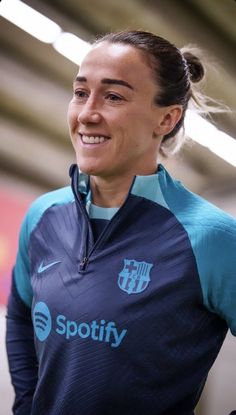 a woman is smiling and wearing a blue shirt with the word spotify on it