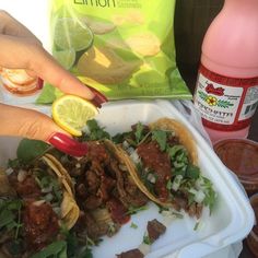 a person holding a plate with tacos and chips on it next to a bag of tortillas