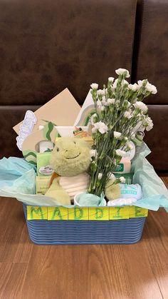 a teddy bear sitting in a basket filled with baby's breath and personal care items