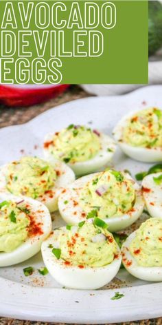 deviled eggs on a white plate with green garnish and red pepper sprinkled on top