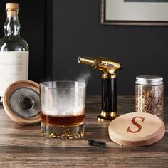 a wooden coaster next to a glass and bottle on a table with some liquor in it