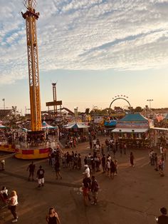 an amusement park filled with lots of people walking around and riding on top of rides