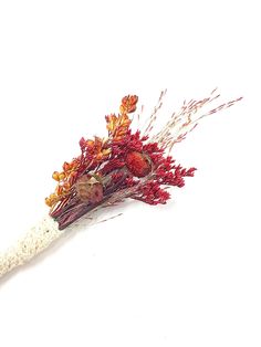 a bouquet of dried flowers sitting on top of a white surface