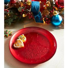 a red plate sitting on top of a table next to christmas decorations and ornaments in the background