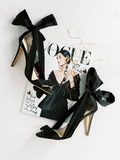 a pair of black high heeled shoes sitting on top of a magazine with a woman's face