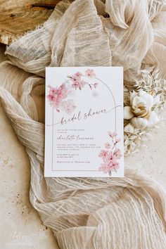 the wedding stationery is laid out on top of sheer fabric and flowers are scattered around it