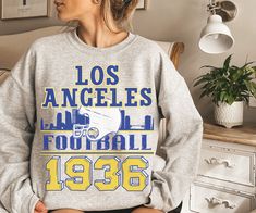 Are you ready for FOOTBALL SEASON?! And are you looking for a unique, retro design that differs from the generic team gear you find elsewhere online? This vintage styled, cute Los Angeles Football sweatshirt is perfect to support your favorite LA team this football season! This crewneck is available in white, ash grey, sport grey, heather grey, sand, and black (pick one up for your husband/boyfriend/best friend/dad/mom etc too!) Sweatshirt details are below, and the models in the pictures are we Retro Fan Gear Tops For Sports Season, Retro Tops For Sports Season Fan Gear, Retro Tops For Football Season Sports Events, Football Fan Shirts, Boyfriend Best Friend, Sweatshirt Details, La Rams, Vintage Los Angeles, White Ash