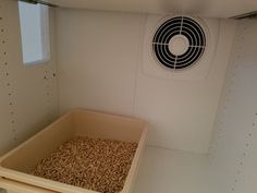 a bird feeder in the corner of a room with a fan on the wall above it