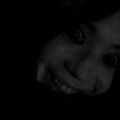 black and white photograph of a woman smiling with her hand on her face in the dark