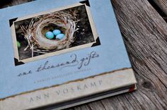 an old book with two blue eggs in the nest on top of it, sitting on a wooden table