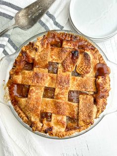 a pie sitting on top of a white table next to a plate and spoons