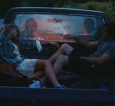 two people are sitting in the back of a pick - up truck and one person is holding a sign that says love