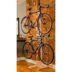 two bikes are mounted to the side of a brick wall in front of a wooden floor