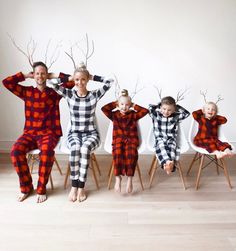 a group of people sitting on top of chairs wearing matching pajamas and reindeer antlers