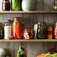 many jars filled with vegetables on wooden shelves