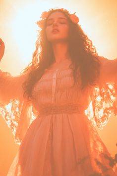 a woman with long hair wearing a dress and holding her hands up in the air