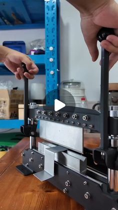 two hands are working on a machine in a shop