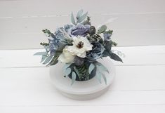 a white vase filled with blue and white flowers