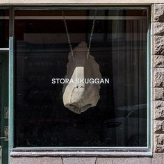 a stone sculpture hanging in the window of a storefront with an advertisement on it