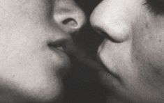 two people are kissing each other with their noses close to one another in black and white