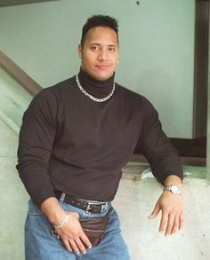 a man in jeans and a turtle neck sweater is posing for a photo with his hands on his hips