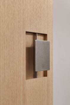 a door handle on a wooden door with a square metal object in the center,