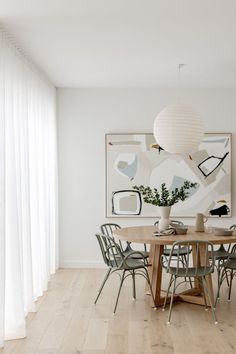 a dining room table with four chairs and a vase on the table in front of it