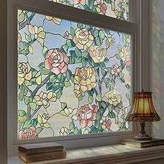 a stained glass window with flowers on it and a lamp in front of the window