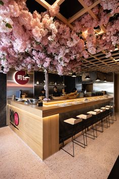 the interior of a japanese restaurant with cherry blossoms on the ceiling and bar stools